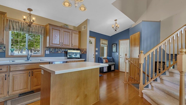 2647 Olive Ln, Sauk Rapids, MN 56379 - kitchen with a chandelier, a sink, wood finished floors, light countertops, and a kitchen island
