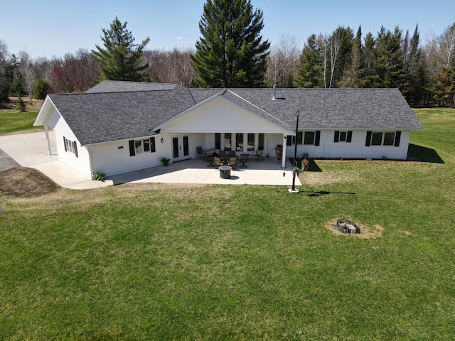 rear view of property featuring french doors, a fire pit, a lawn, a patio, and roof with shingles