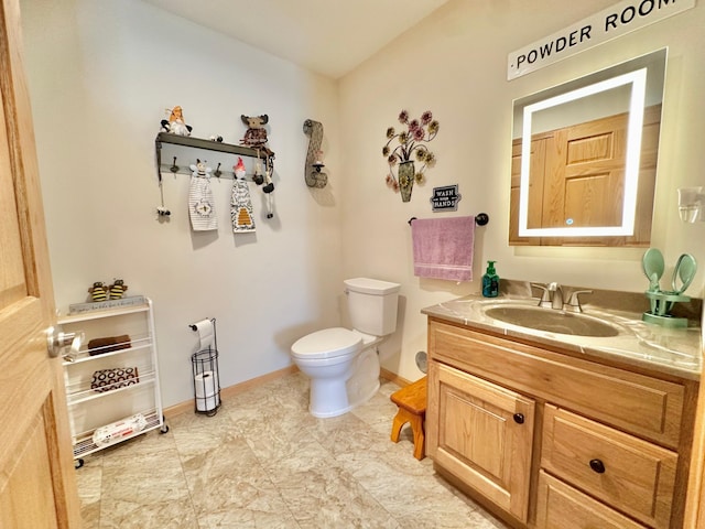 bathroom with toilet, vanity, and baseboards