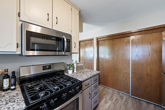 11123 Drake St NW, Coon Rapids, MN 55433 - kitchen featuring appliances with stainless steel finishes, light wood-type flooring, and a textured ceiling