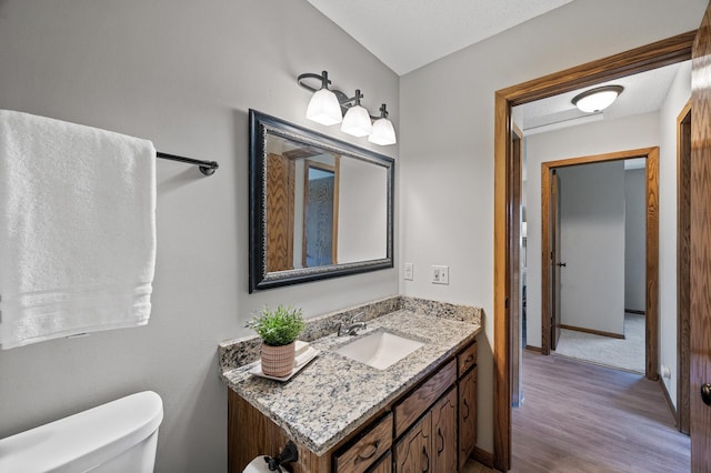 11123 Drake St NW, Coon Rapids, MN 55433 - bathroom with wood finished floors, toilet, vanity, and baseboards