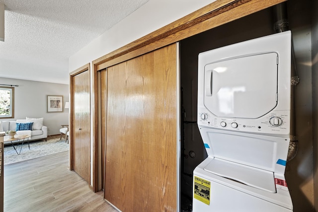 11123 Drake St NW, Coon Rapids, MN 55433 - washroom featuring stacked washer and clothes dryer, light wood-style floors, and a textured ceiling