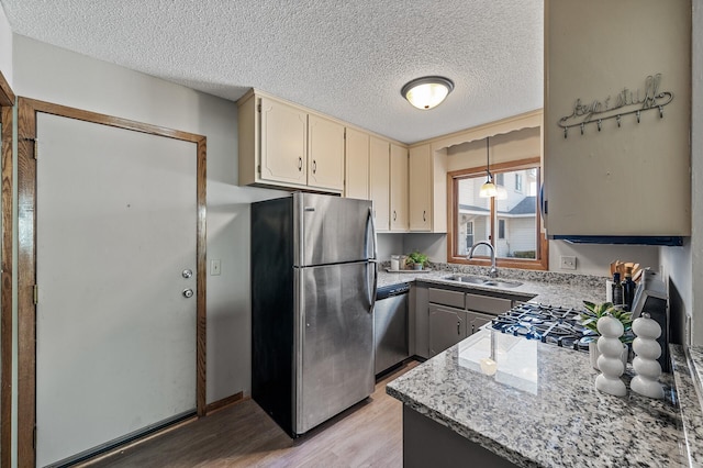 11123 Drake St NW, Coon Rapids, MN 55433 - kitchen featuring stainless steel appliances, a sink, light wood finished floors, a textured ceiling, and light stone countertops