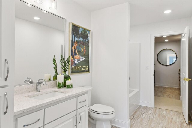 bathroom featuring vanity, wood finished floors, toilet, and recessed lighting