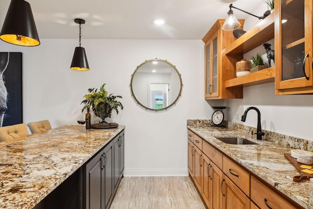 kitchen with a sink, open shelves, light stone counters, baseboards, and recessed lighting