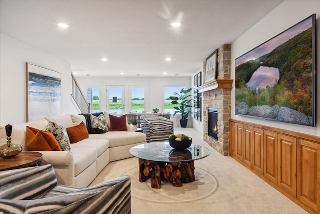 living area with a stone fireplace, recessed lighting, and light carpet