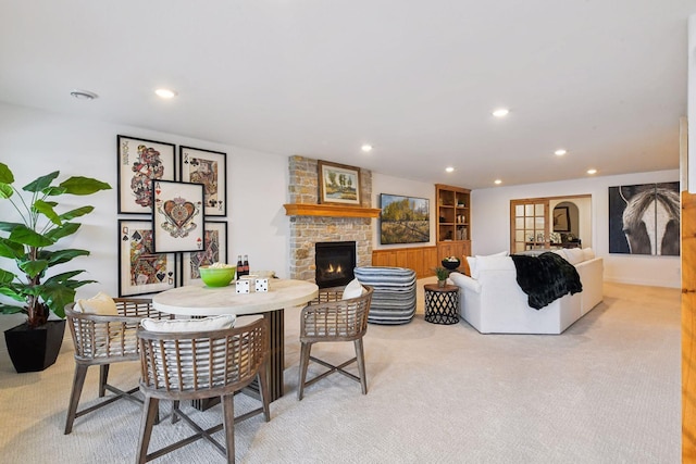 living area with light colored carpet, a stone fireplace, and recessed lighting