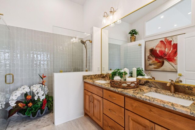 bathroom featuring tiled shower, double vanity, and wood finished floors