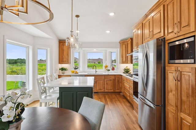 kitchen with appliances with stainless steel finishes, a sink, light countertops, light wood-type flooring, and plenty of natural light