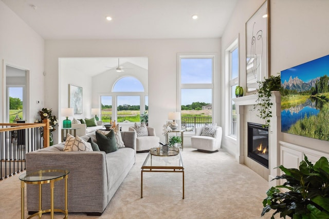 carpeted living area with a glass covered fireplace, ceiling fan, recessed lighting, and a high ceiling