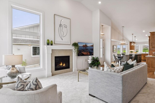 living room with lofted ceiling, a chandelier, a tiled fireplace, and recessed lighting