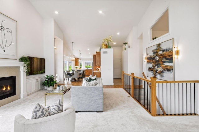 living room featuring high vaulted ceiling, recessed lighting, and a glass covered fireplace