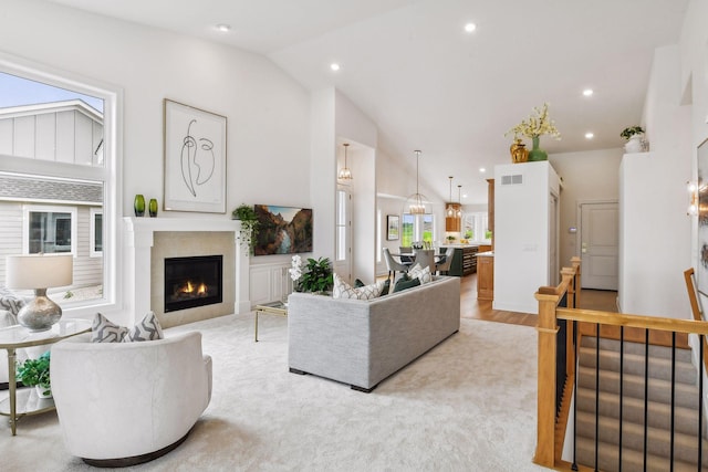 living room with a tile fireplace, vaulted ceiling, recessed lighting, and light wood-style floors