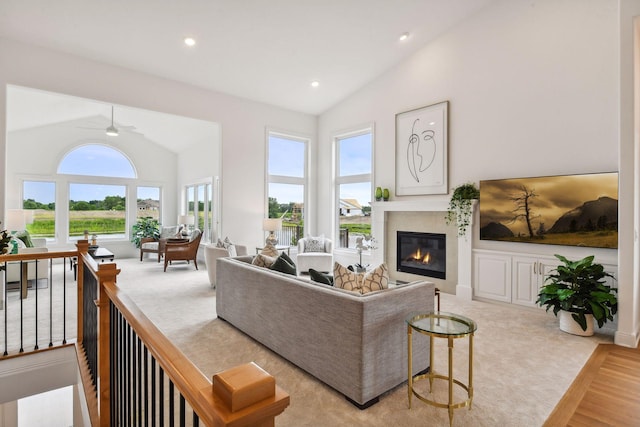 living area featuring a glass covered fireplace, ceiling fan, wood finished floors, high vaulted ceiling, and recessed lighting