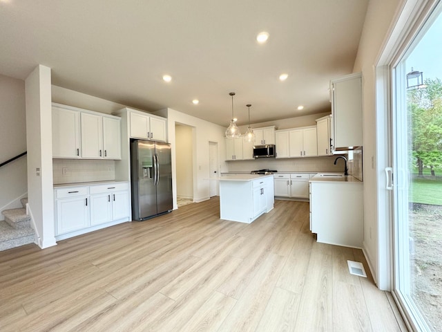 7499 Odell Ave NE, Otsego, MN 55330 - kitchen featuring appliances with stainless steel finishes, a kitchen island, backsplash, light countertops, and light wood-style flooring