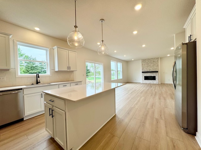 7499 Odell Ave NE, Otsego, MN 55330 - kitchen featuring appliances with stainless steel finishes, a sink, light wood-style floors, decorative backsplash, and a center island