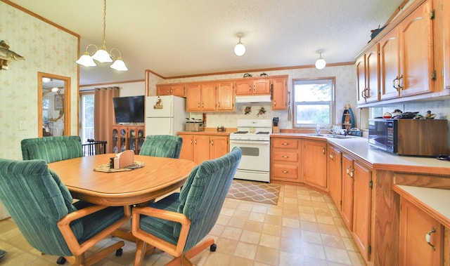 kitchen with white appliances, wallpapered walls, under cabinet range hood, ornamental molding, and hanging light fixtures