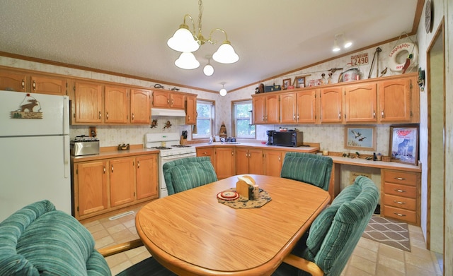 kitchen featuring white appliances, lofted ceiling, under cabinet range hood, ornamental molding, and a chandelier