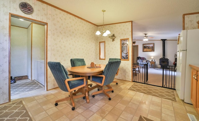 dining space featuring a wood stove, wallpapered walls, crown molding, washer / clothes dryer, and ceiling fan