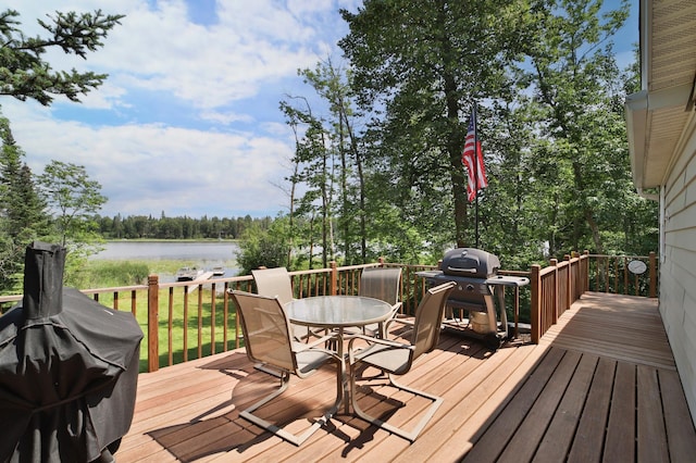 wooden deck featuring outdoor dining area, a water view, and a grill