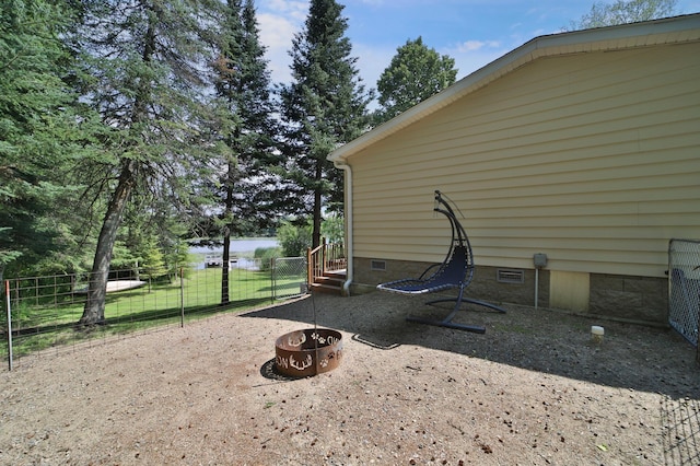 view of patio / terrace with fence, a fire pit, and a water view