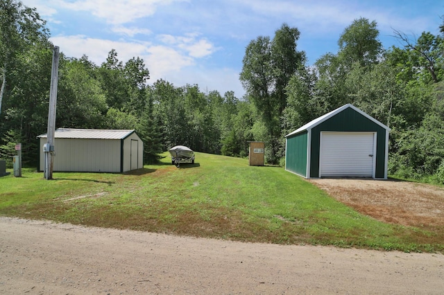 view of green lawn with an outbuilding, a detached garage, and driveway