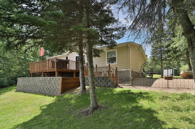 rear view of property with a yard, a wooden deck, an outdoor structure, and a shed