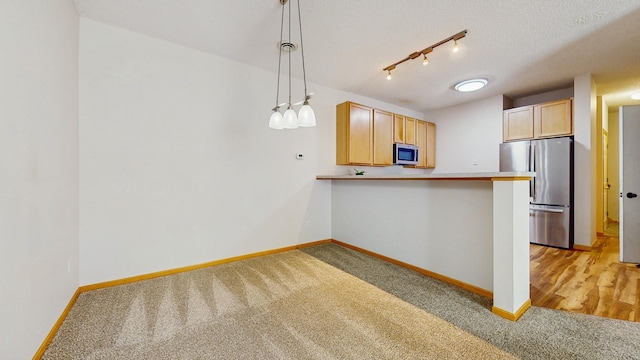 kitchen with appliances with stainless steel finishes, light carpet, baseboards, a peninsula, and pendant lighting
