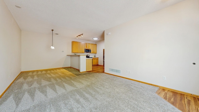 unfurnished living room featuring light colored carpet, baseboards, and a textured ceiling