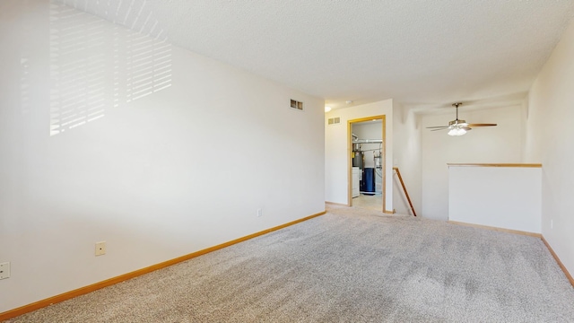 empty room featuring light colored carpet, baseboards, a ceiling fan, and a textured ceiling