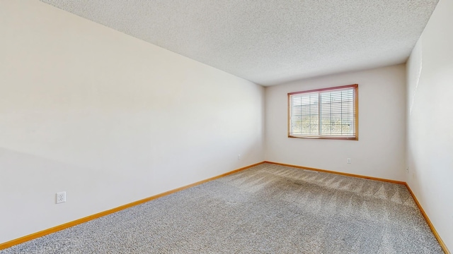 unfurnished room featuring a textured ceiling, light carpet, and baseboards