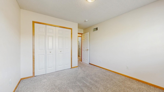 unfurnished bedroom featuring baseboards, carpet floors, a closet, and a textured ceiling