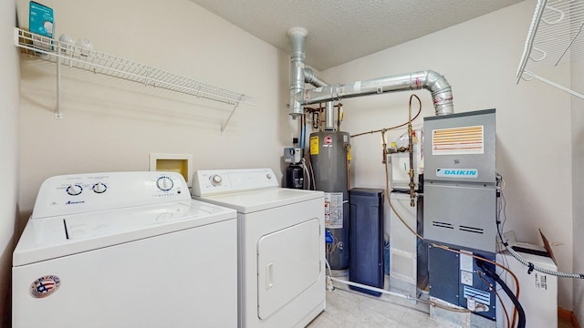 laundry room with washer and dryer, water heater, light tile patterned floors, and a textured ceiling