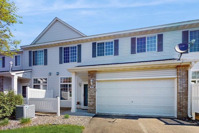 townhome / multi-family property featuring a garage, asphalt driveway, and central AC unit