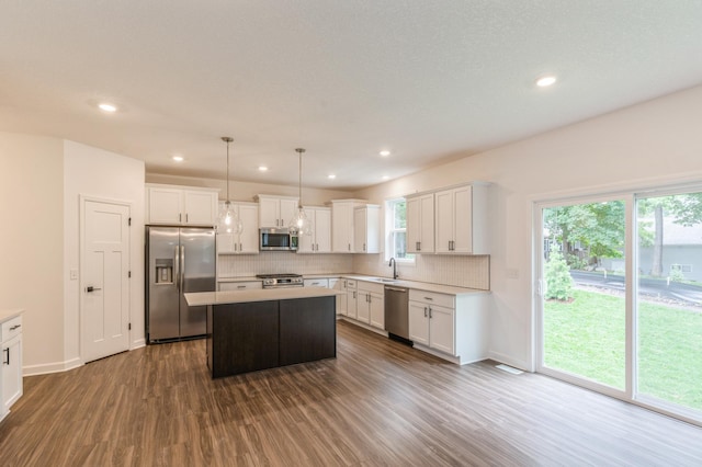 kitchen featuring stainless steel appliances, dark wood-style floors, decorative backsplash, a kitchen island, and light countertops