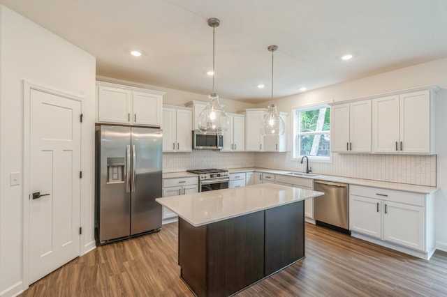 kitchen with stainless steel appliances, a sink, dark wood-style flooring, white cabinetry, and decorative backsplash