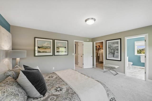 bedroom with a spacious closet, carpet, connected bathroom, and baseboards