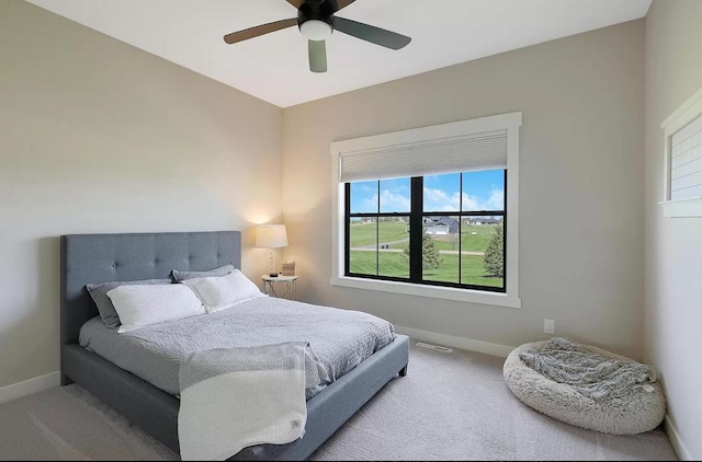 carpeted bedroom featuring baseboards, multiple windows, and a ceiling fan