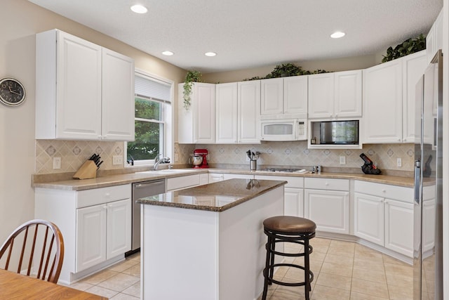 17462 Haralson Dr, Eden Prairie, MN 55347 - kitchen with appliances with stainless steel finishes, light tile patterned floors, a center island, recessed lighting, and white cabinetry
