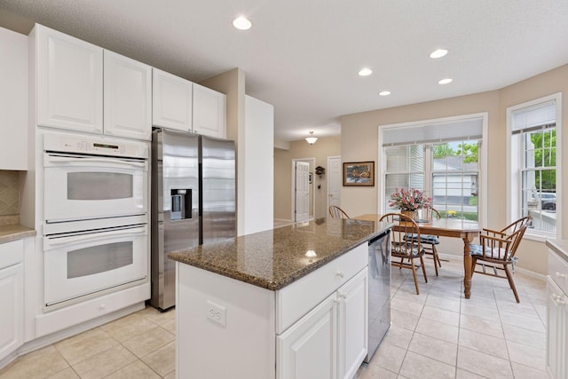 17462 Haralson Dr, Eden Prairie, MN 55347 - kitchen with appliances with stainless steel finishes, a kitchen island, recessed lighting, light tile patterned flooring, and dark stone countertops