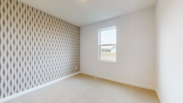 spare room featuring wallpapered walls, light colored carpet, and baseboards