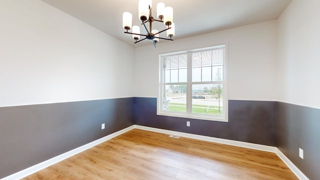unfurnished room featuring a chandelier, light wood-style flooring, and baseboards