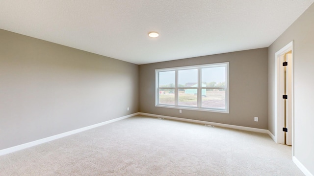empty room featuring light carpet and baseboards