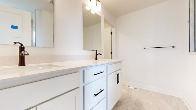bathroom featuring double vanity, marble look tile flooring, and baseboards