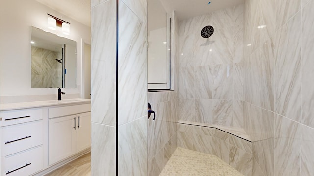 full bathroom with a tile shower and vanity