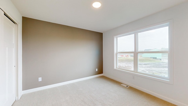 unfurnished room with light carpet and baseboards