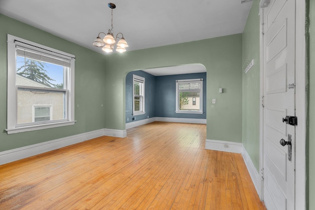 822 35th St, Minneapolis, MN 55408 - unfurnished room with arched walkways, baseboards, light wood-style flooring, and a chandelier