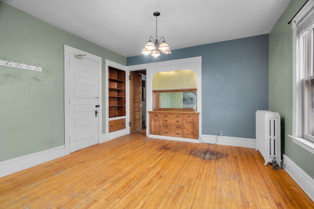 822 35th St, Minneapolis, MN 55408 - unfurnished dining area featuring radiator, a chandelier, hardwood / wood-style flooring, and baseboards
