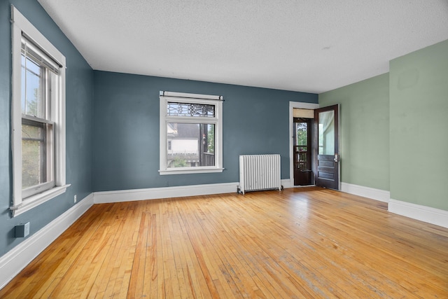 822 35th St, Minneapolis, MN 55408 - spare room featuring radiator heating unit, hardwood / wood-style flooring, a textured ceiling, healthy amount of natural light, and baseboards