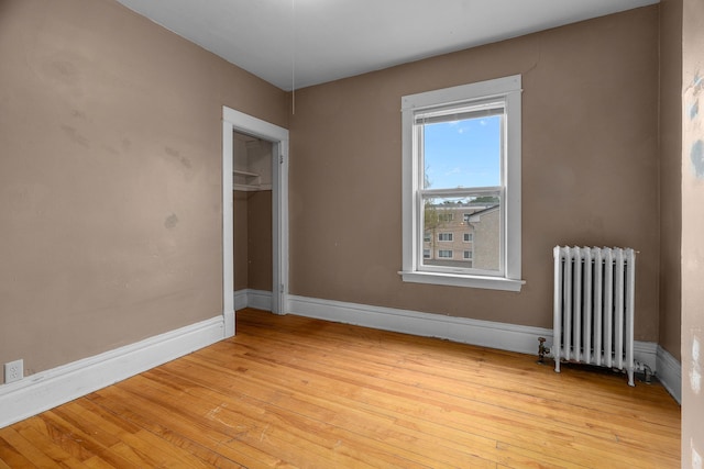 822 35th St, Minneapolis, MN 55408 - empty room with radiator heating unit, light wood-style flooring, and baseboards